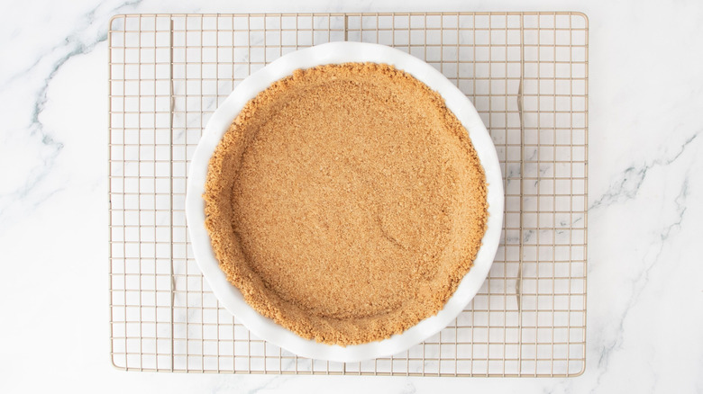 Graham cracker crust in pie dish on wire rack