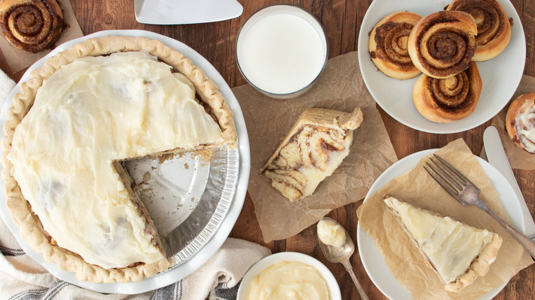 Cinnamon roll pie with slices removed next to unfrosted cinnamon rolls