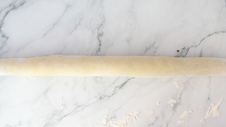 Long dough cylinder on floured surface