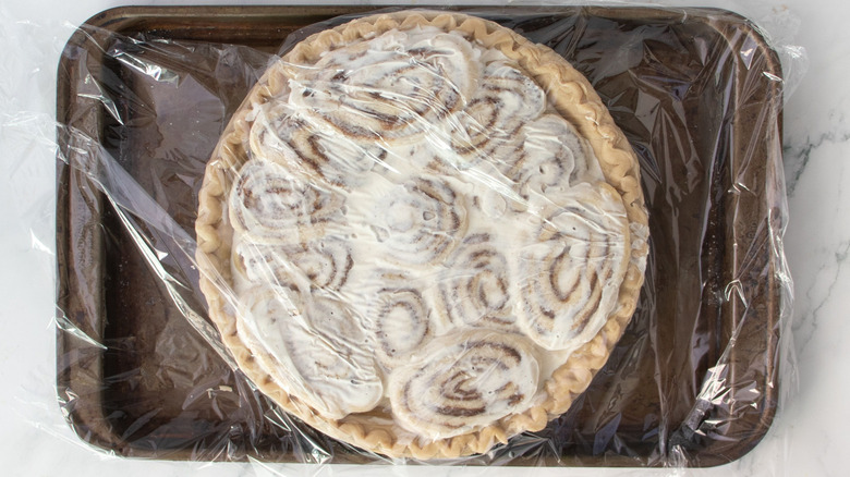 Unbaked cinnamon roll pie covered with plastic wrap