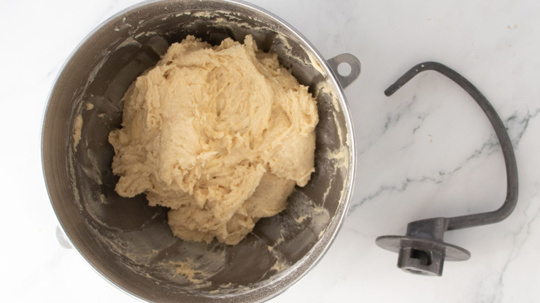Shaggy dough in mixing bowl next to dough hook