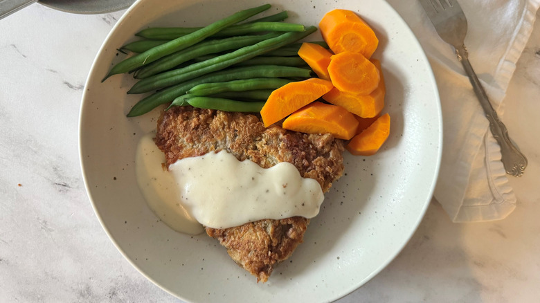 Country fried steak, carrots, and green beans on plate
