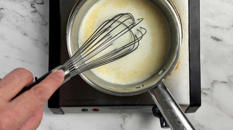 Hand whisking gravy mixture in saucepan