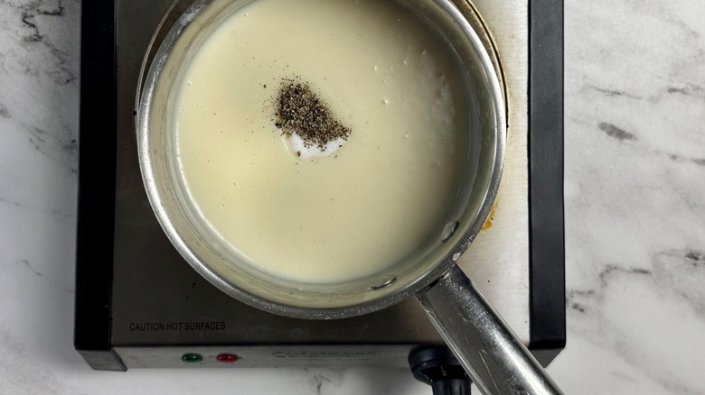 White gravy in saucepan with salt and pepper
