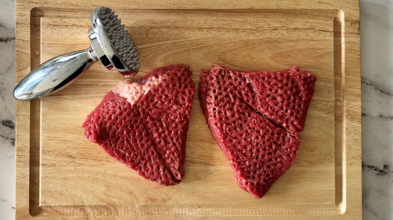 Meat mallet and pounded steaks on cutting board