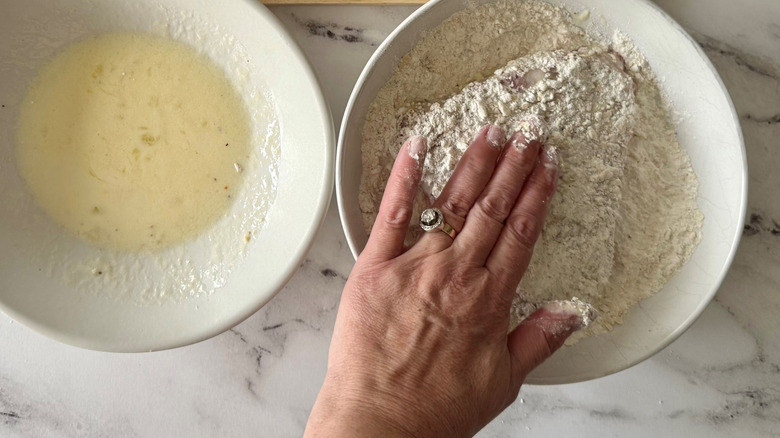 Hand pressing steak into flour mixture