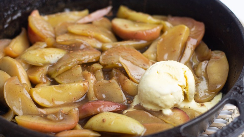 plate of fried apples coated in sauce with ice cream