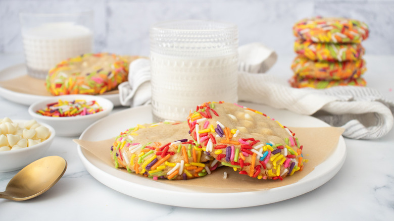 Copycat Crumbl cake batter blondie cookies with sprinkles on plate in front of glass of milk