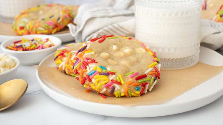 Copycat Crumbl blondie cookies with colorful sprinkles on plate with glass of milk