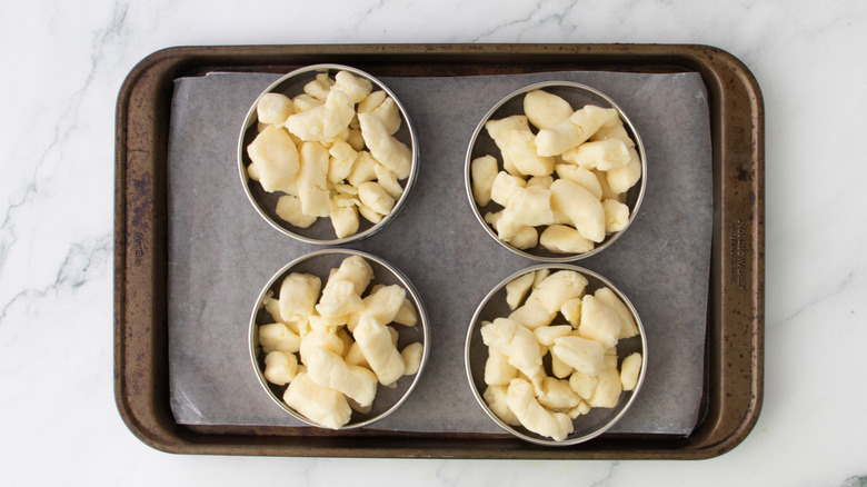 cheese curds portioned into four ring molds on baking sheet