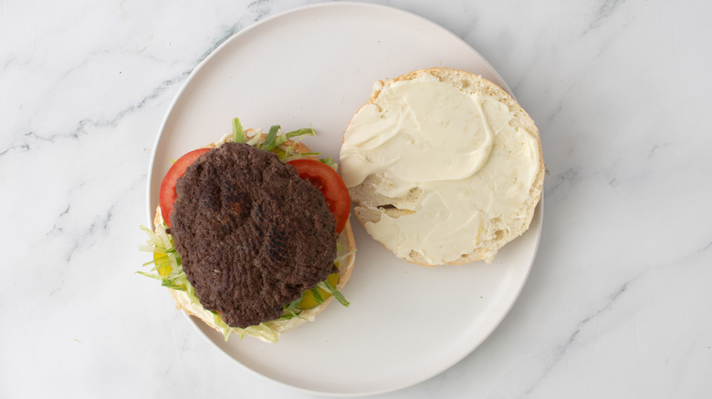 halved burger buns with vegetables and patty