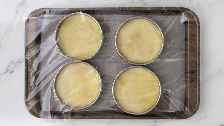 melted cheese curds in ring molds covered in plastic wrap