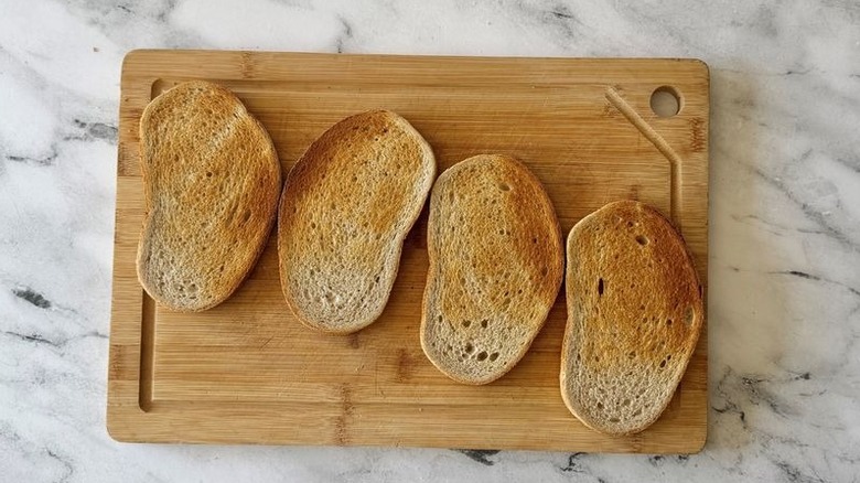Four slices of toasted rye bread on wooden board