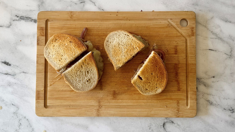 Halved patty melt sandwiches on wooden board