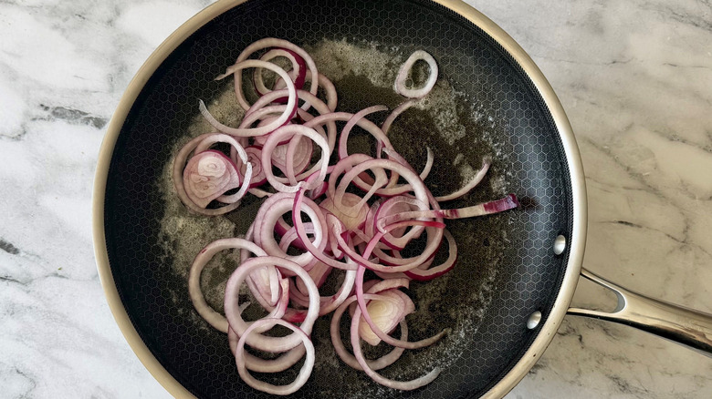 Sliced red onions cooking in skillet