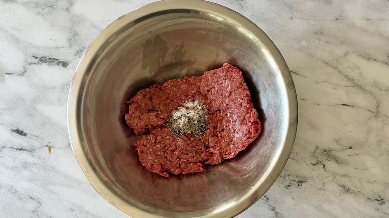 Ground beef, salt, and pepper in bowl