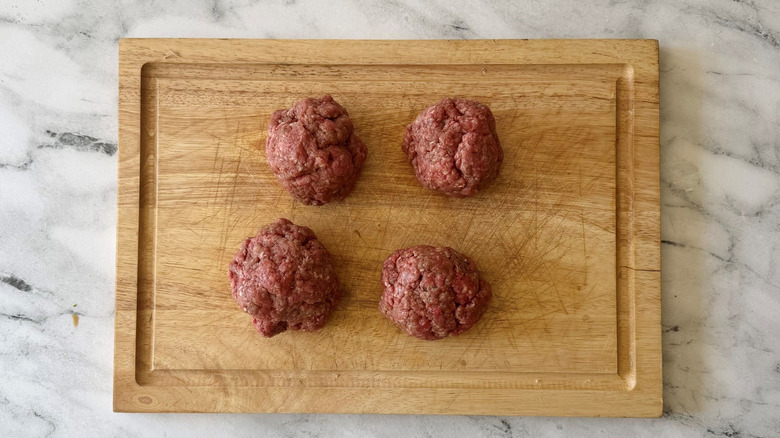 Four ground beef balls on wooden board