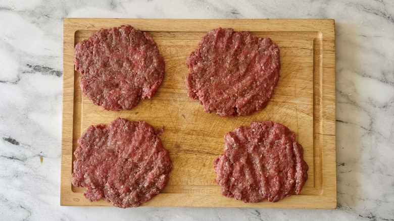 Beef patties on wooden board