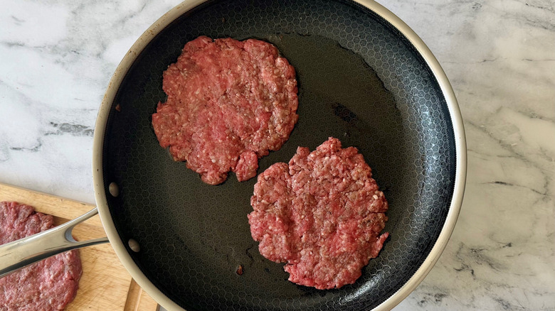 Raw beef patties in skillet