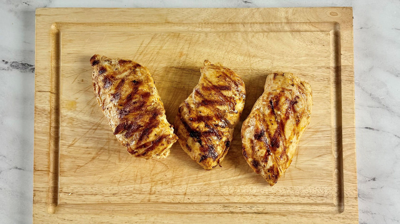 Grilled chicken breasts on wooden board