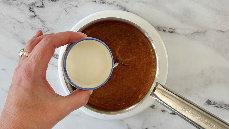 Hand adding cornstarch slurry to sauce