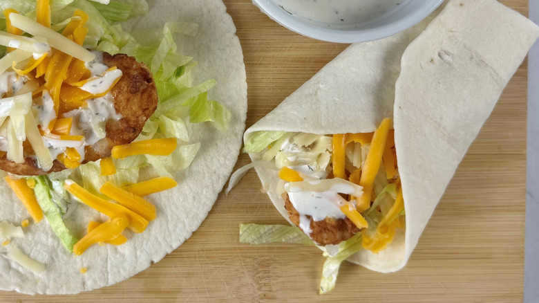 Unwrapped and wrapped chicken Snack Wraps on wooden board