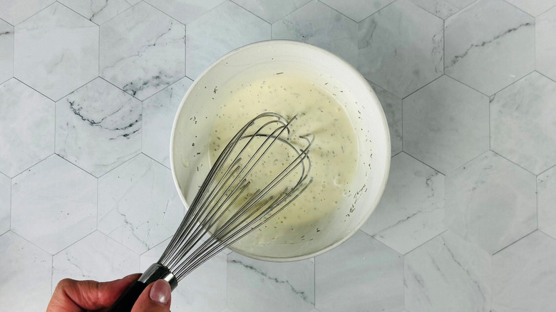Hand whisking ranch dressing in bowl