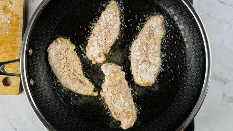 Chicken tenders frying in pan