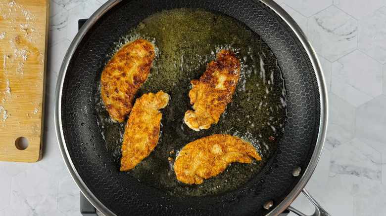 Chicken tenders frying in pan