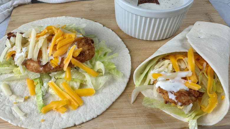 Unwrapped and wrapped chicken snack wraps on wooden board