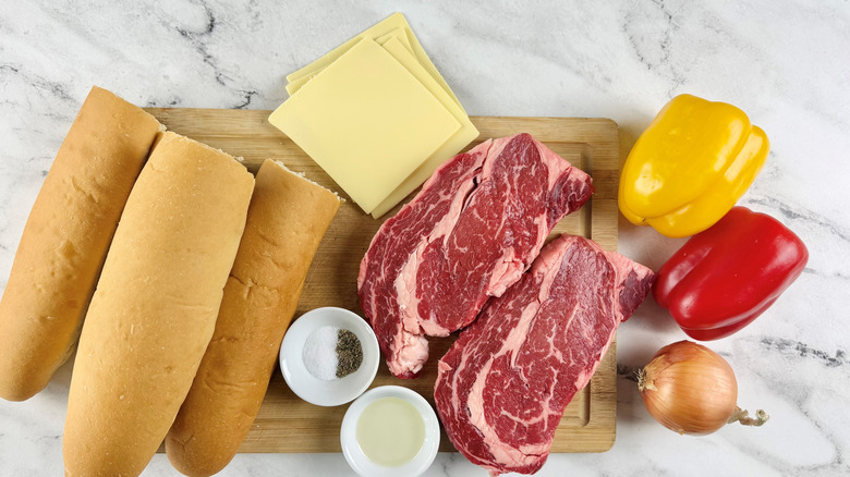 ingredients for a steak and cheese sandwich with peppers and onions