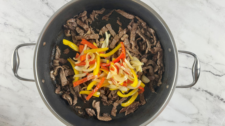 cooked meat and vegetables in a black frying pan