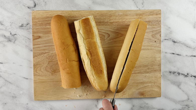 hand sticking a knife in a bread roll