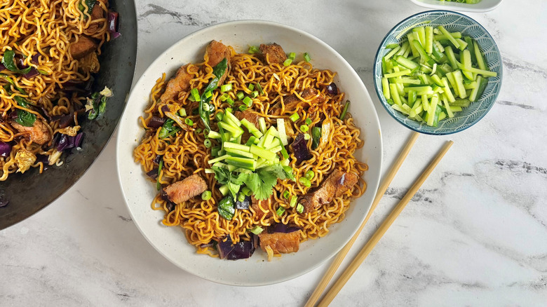 ramen noodles with steak strips and green onions in a white bowl