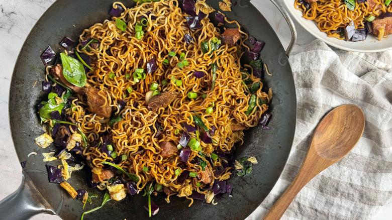 ramen noodles with steak strips and green onions in a round pan