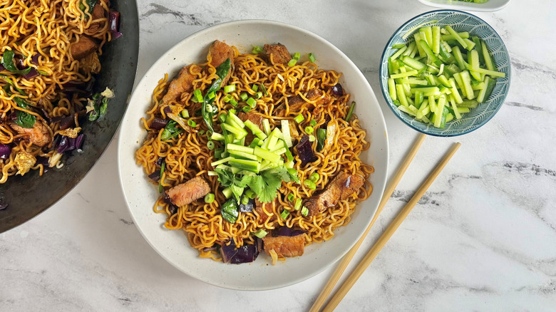 ramen noodles with steak strips and green onions in a white bowl