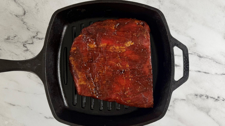 raw steak in a square black frying pan