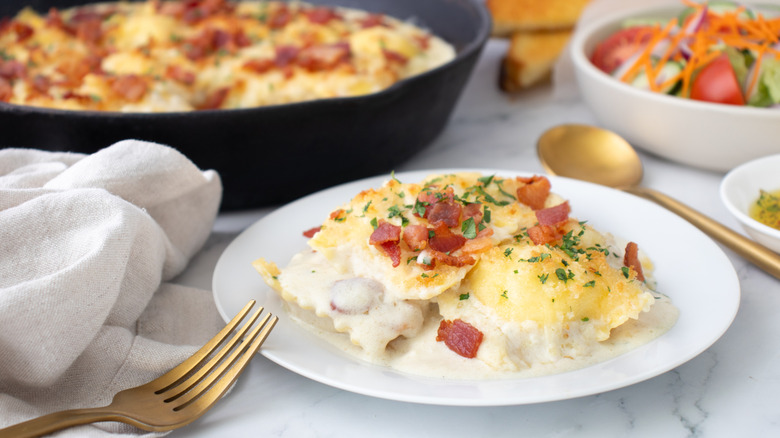 cheesy pasta with bacon on a white plate