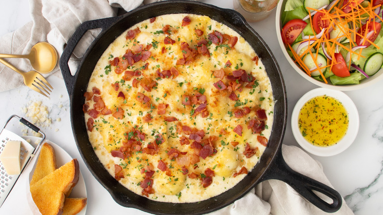 cheesy pasta with bacon in a black frying pan