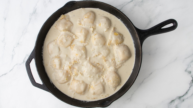 pasta in creamy sauce with cheese in a black frying pan
