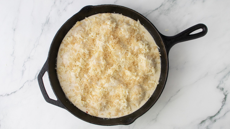 pasta in creamy sauce with cheese and breadcrumbs in a black frying pan