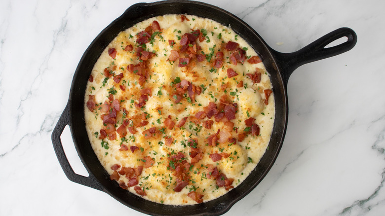 cheesy pasta with bacon in a black frying pan