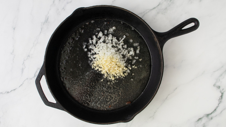 chopped onion and garlic in a black frying pan