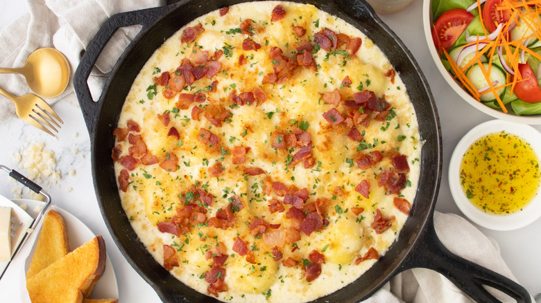 cheesy pasta with bacon in a black frying pan