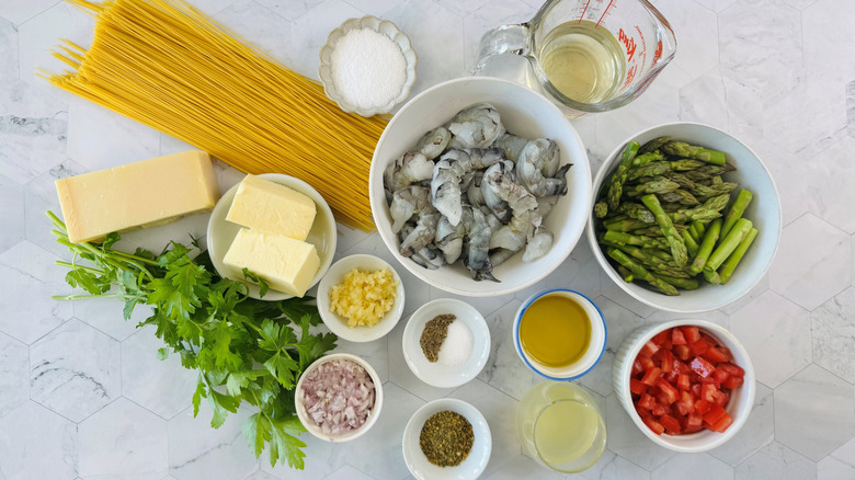 Pasta, butter, raw shrimp, asparagus, diced tomatoes, and other ingredients for copycat Olive Garden shrimp scampi laid out