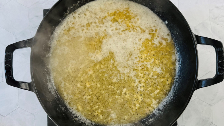 Steam coming from buttery white wine sauce in large pan
