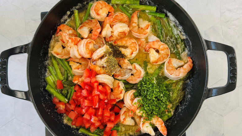 Unmixed shrimp scampi with shrimp and vegetables in melted butter and wine in large pan