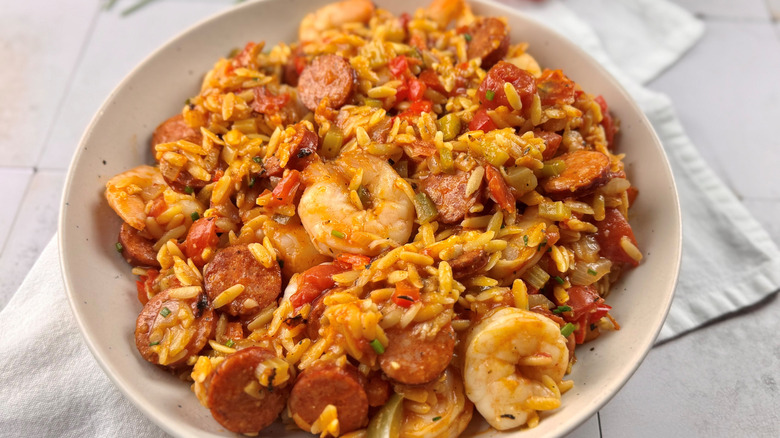 shrimp, sausage, tomatoes, and pasta in a white bowl
