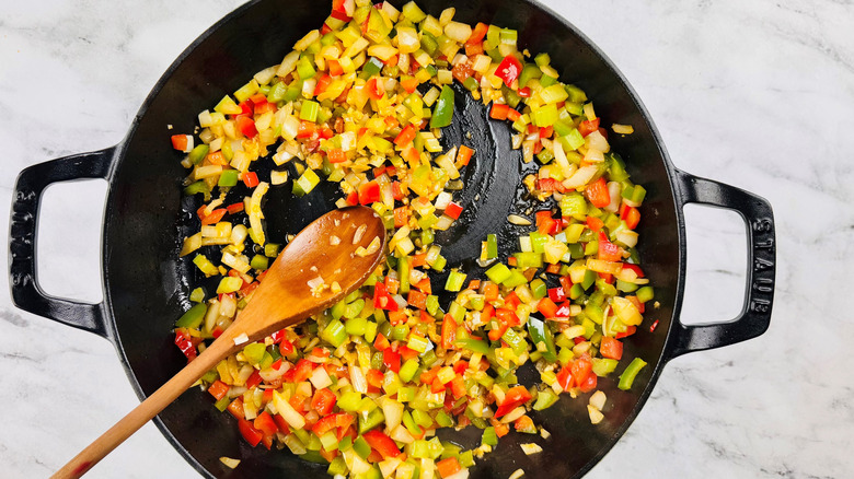 chopped vegetables in a black pot with a wooden spoon