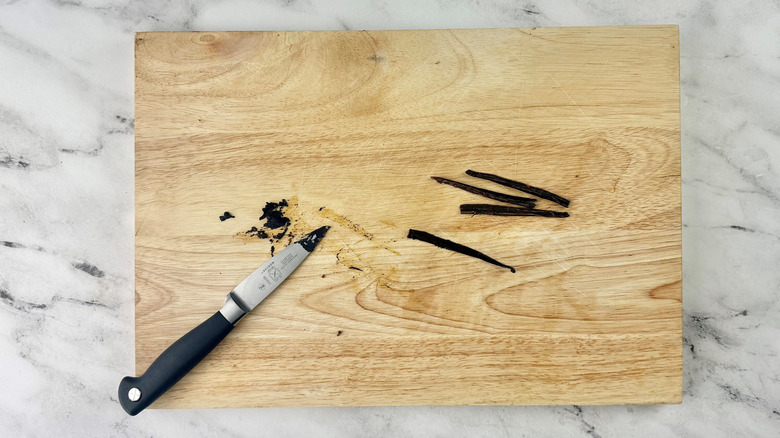 Vanilla beans and knife on cutting board